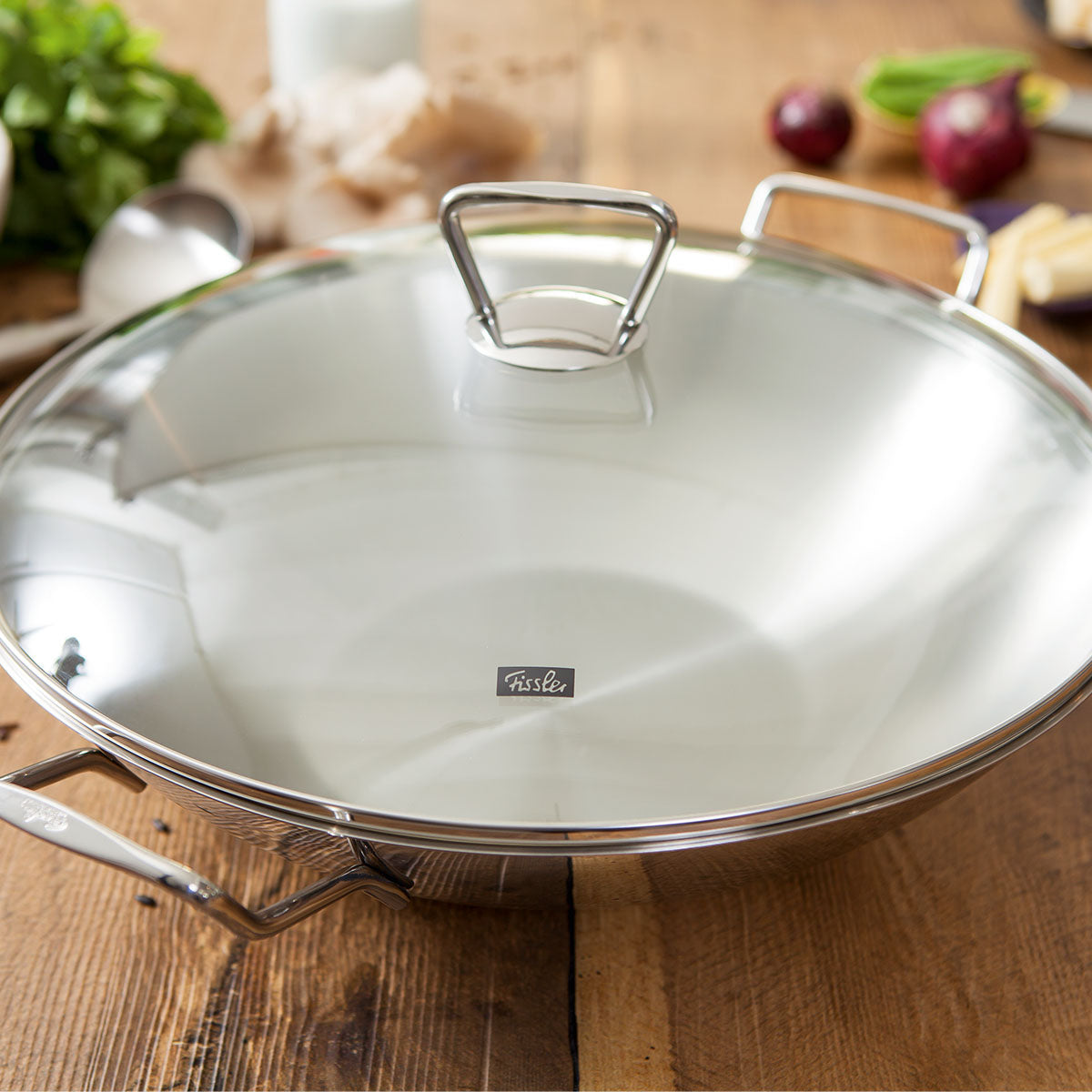 Fissler Kunming Wok with Glass Lid 36 cm, Stainless Steel, Timeless Design, on Wooden Table - Quality "Made in Germany".