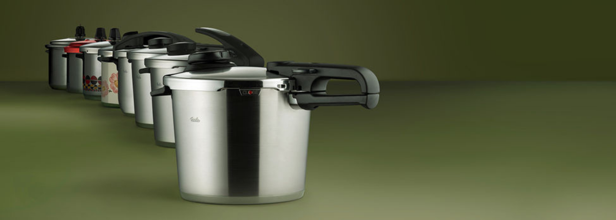 Sechs Fissler Schnellkochtöpfe aus rostfreiem Stahl in einer diagonalen Reihe, jeder mit einzigartigem, in Deutschland entwickeltem Deckel- und Griffdesign.