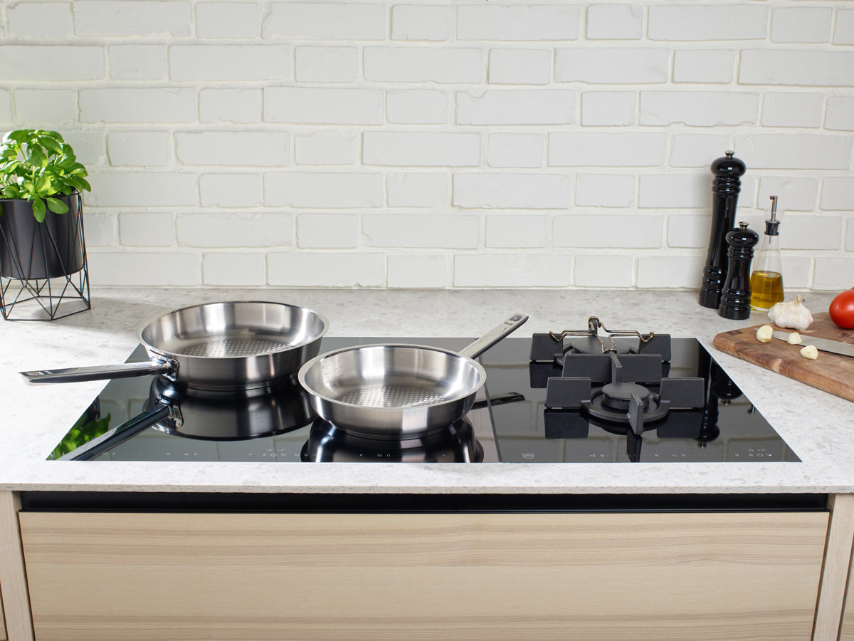 Zwei Fissler Original-Profi Collection® Stielpfannen auf Induktionskochfeld, die deutsche Präzisionsqualität in einer modernen Küche unterstreichen.