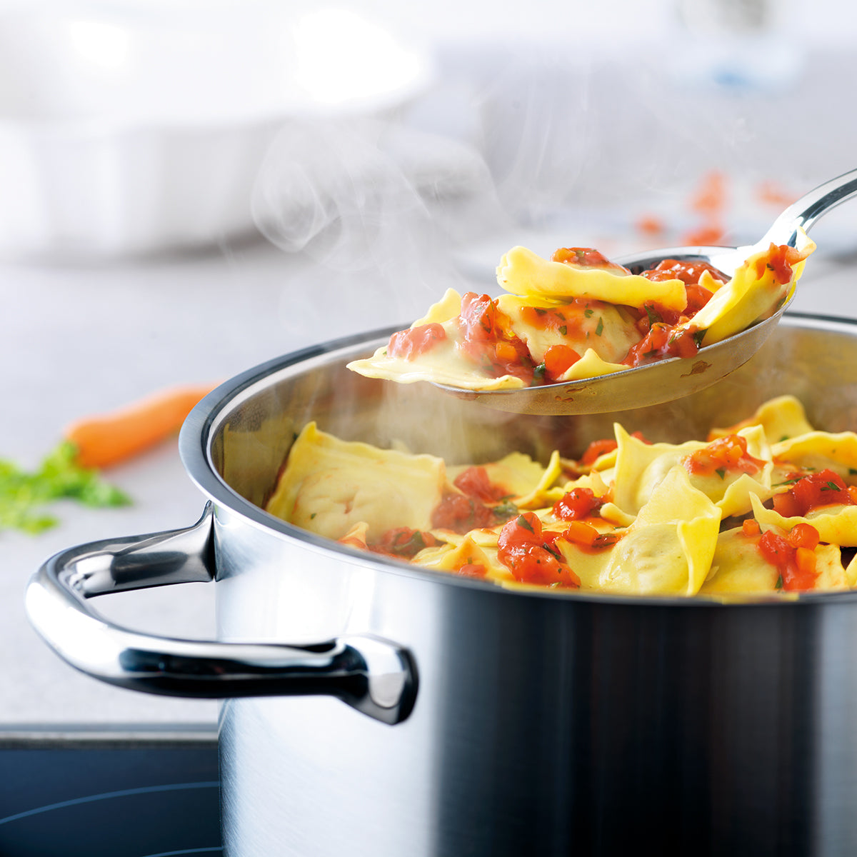 Gelbe Ravioli in Tomatensoße werden in einem Topf der Fissler Family Line gerührt - Präzision, Langlebigkeit und zeitloses deutsches Design werden gezeigt.