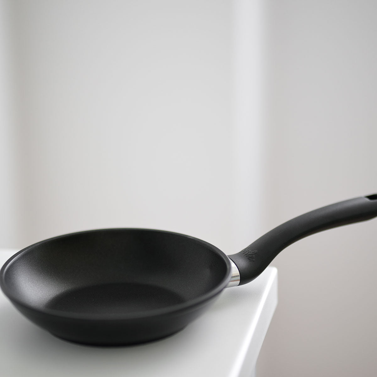 Fissler Cenit® Snack Pan 18 cm, antihaftbeschichtet, modern geschwungener Griff, auf weißer Oberfläche mit sanft verschwommenem Hintergrund.