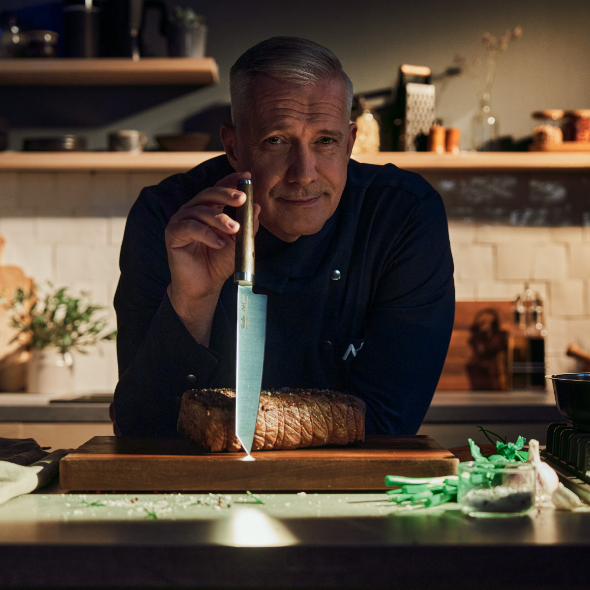 A chef with a Fissler knife prepares a steak on a wooden cutting board, demonstrating German precision and quality in a bright kitchen.